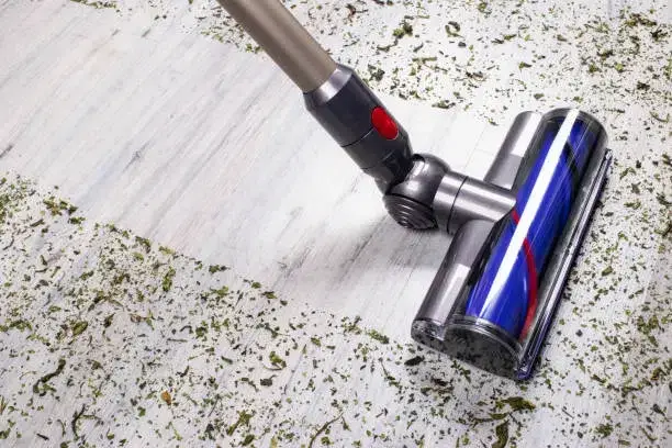 Vacuum cleaner removing debris from a textured white floor. -best floor cleaner